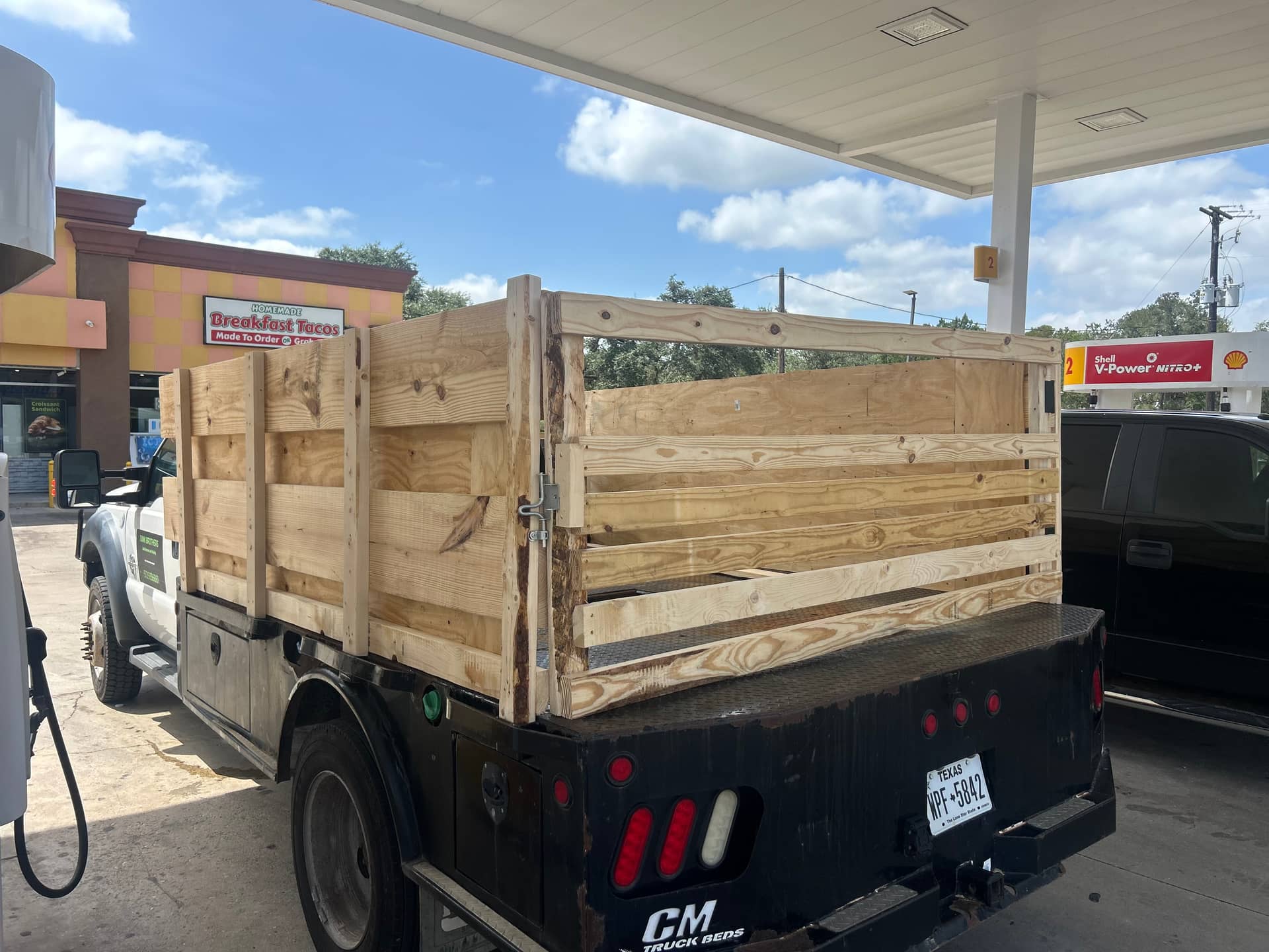 The Junk Brothers flatbed with custom-built wood stake sides, parked in Dripping Springs, Texas